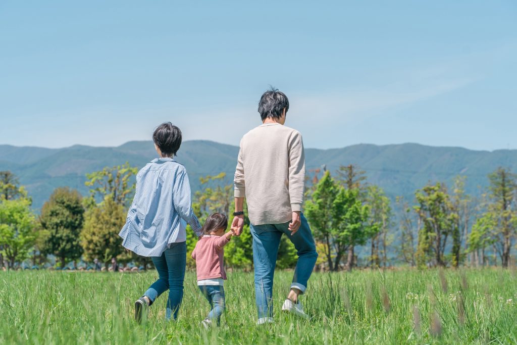 公園・草原を歩く家族・ファミリーの後ろ姿のよの様子