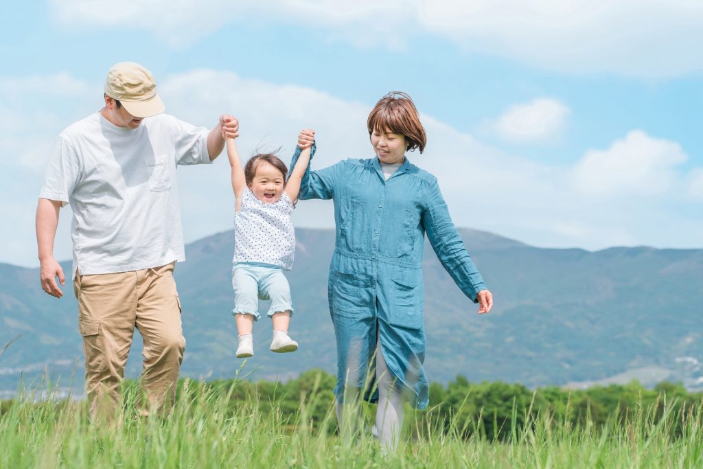 公園を手を繋いでジャンプしながら歩く家族の様子