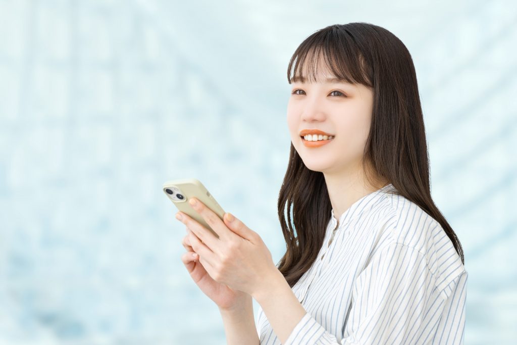 スマホを持つ笑顔の女性・ビジネスウーマンの様子