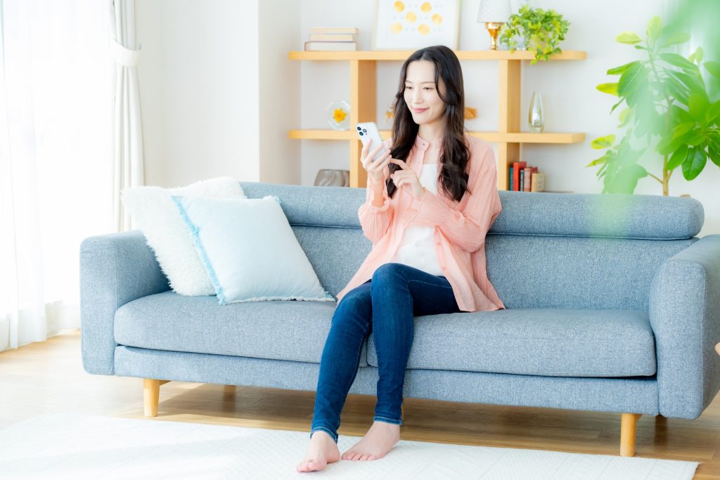 部屋でスマホを操作する女性の様子