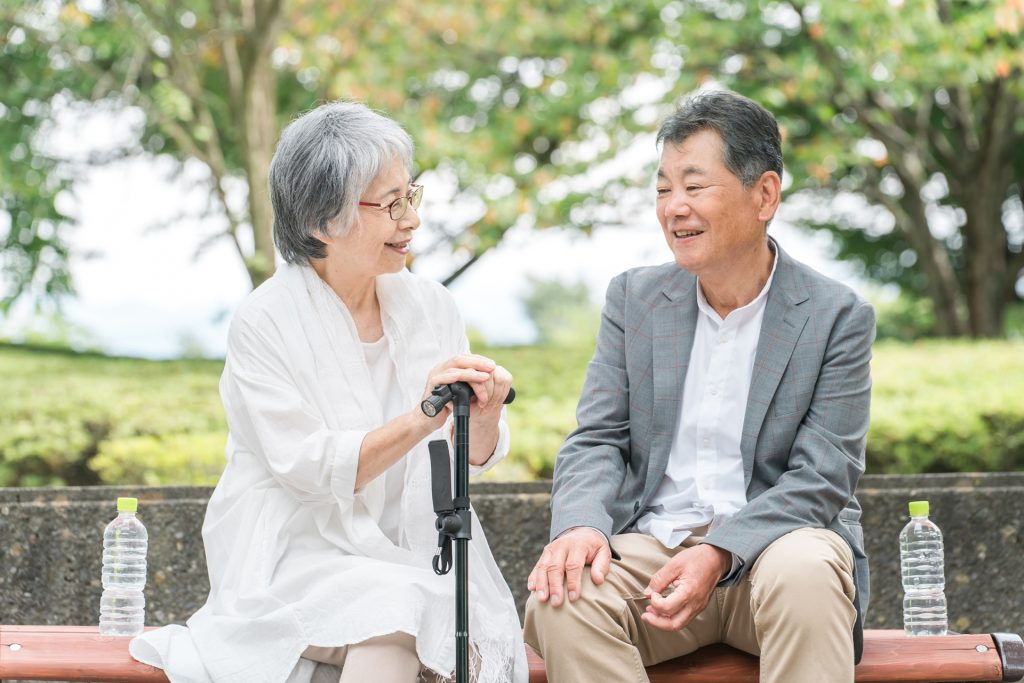 公園のベンチで休憩・会話するシニア夫婦の様子