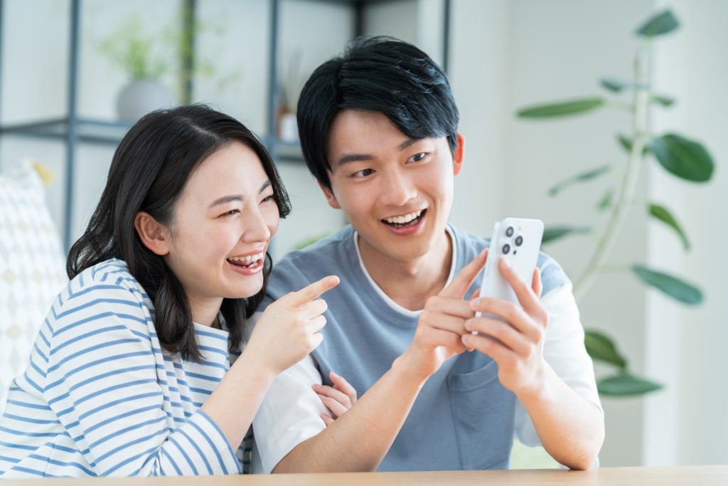 リビングでスマホを見る若い夫婦の様子